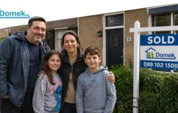 Family standing in front of a sold Dutch house with a Domek SOLD sign
